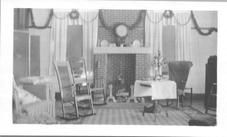 SA0491 - Shows Christmas decorations in the music room; garlands, rocking chairs, fireplace; identified on reverse., Winterthur Shaker Photograph and Post Card Collection 1851 to 1921c
